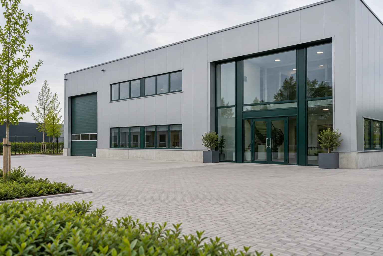 Bedrijfshal met lichte gevelpanelen en groene kozijnen